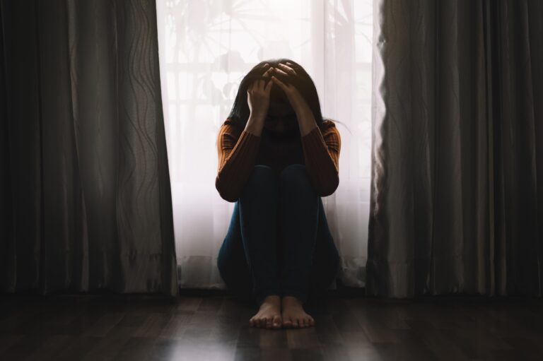 woman with head in hands with head bowed anxious fearful