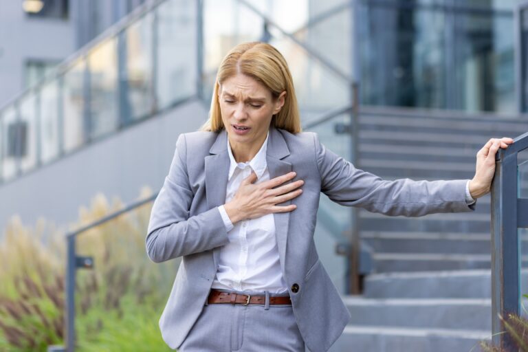 blonde woman in business suit clutching chest with anxiety